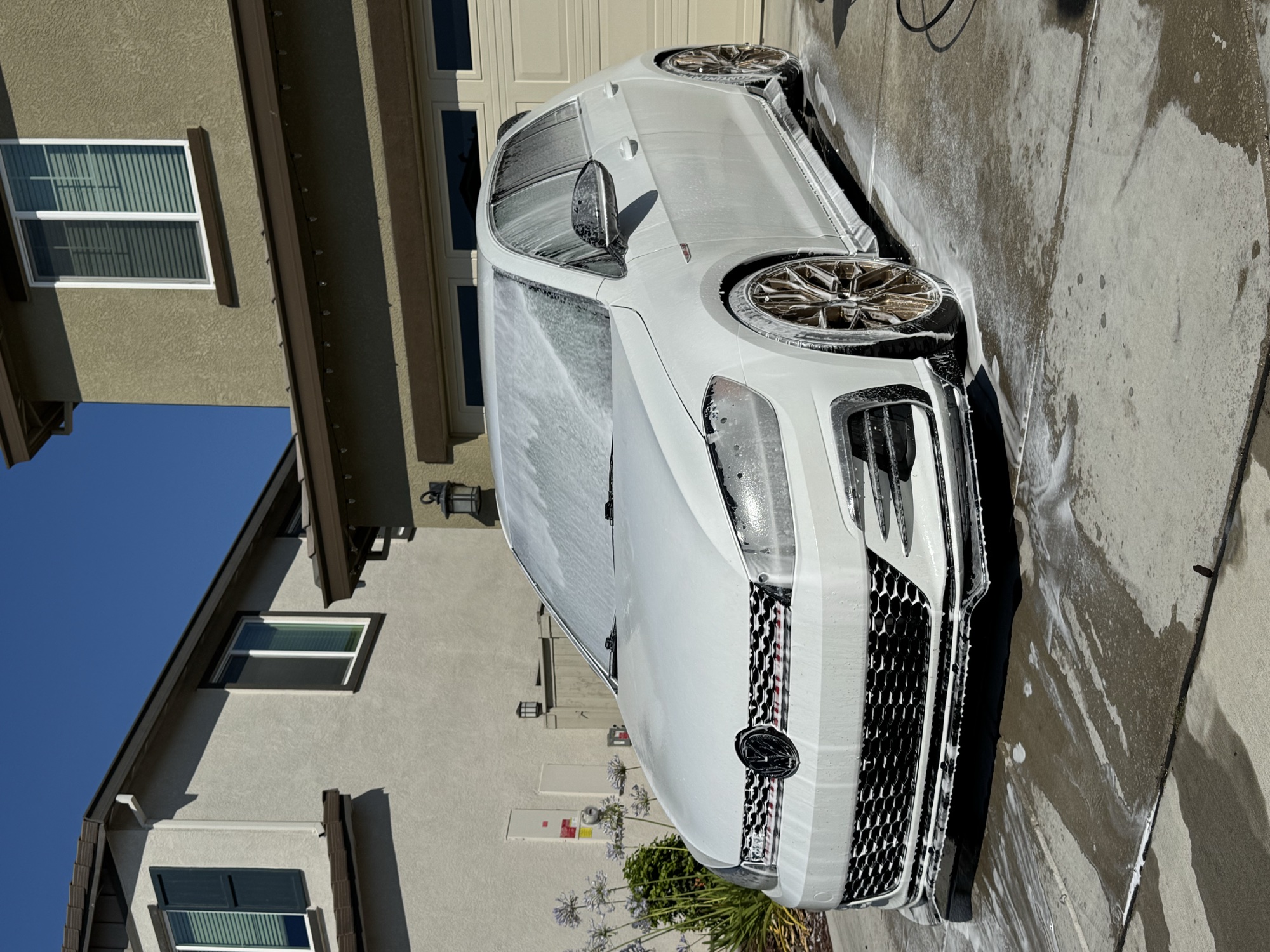 Freshly foamed white Volkswagen GTI being detailed in a Sacramento-area driveway