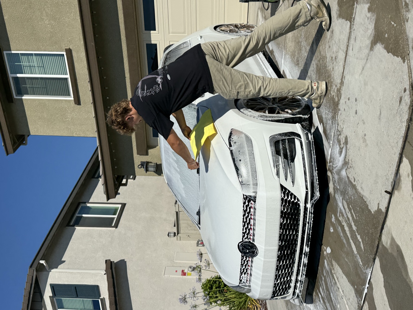 Exclusive Detailing crew hand-washing a foam-covered car in a driveway